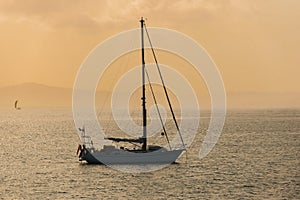 Sailing yacht against sunset tinted in warm tones