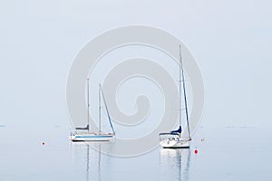 Sailing yacht in the blue sea with sails down, summer landscape