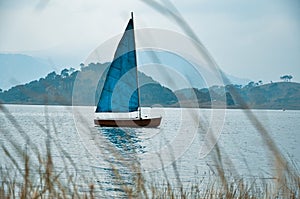 Sailing yacht boat in the foggy sea against mountains landscape