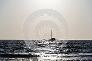 A sailing yacht or boat in the horizon of seascape in summer in sunset