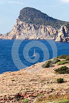 Sailing yacht on bright blue water of Mediterranean Sea against the backdrop of a rearing headland of Cap Nuno Nono