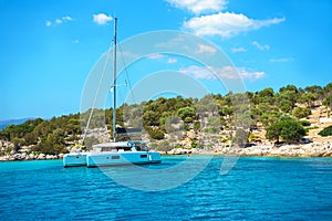 Sailing yacht catamaran boat with white sails on turquoise waters of sea.