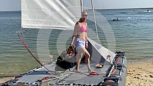 Sailing yacht, regatta. Happy young woman is going to sail on catamaran, summer vacation on a sailing boat. Collecting