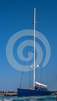 A sailing yacht with a retracted sail is at the pier. The mast is equipped with navigation, weather and radio