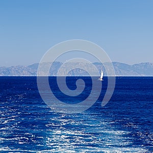 Sailing yacht at sea on the background of mountains and the track of the ship engine