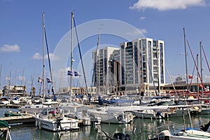 Sailing yachts and modern buildings in Herzliya Marina, Israel.