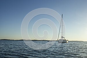 Sailingboat anchored on calm sea near islands