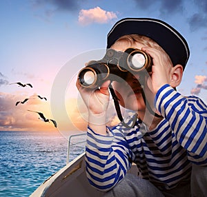 Sailor boy with binoculars in the boat