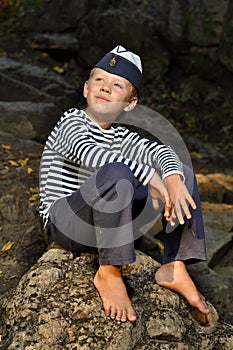 Sailor boy sitting on a stone