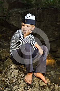 Sailor boy sitting on a stone