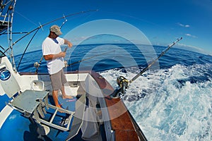 Sailor gets ready reels and rods for marlin game fishing at sea near Saint-Denis, Reunion island.