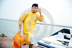 Sailor man in yellow cloak walking at the sea pier