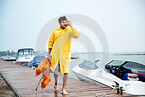 Sailor man in yellow cloak walking at the sea pier