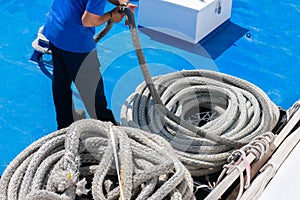 Sailor on the ship is giving mooring in the port. The rope is coiling and wounding in a spiral photo