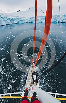 Sailor standing on mast of sailing boat yacht in Antarctica, adventure travel