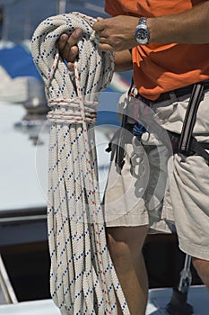 Sailor Tying Ropes On Sailboat