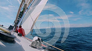 Sailors on deck of yacht or sailboat secure sail