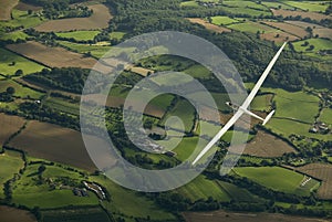 Sailplane soaring across the countryside.