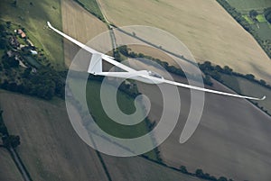 Sailplane soaring over farmland.