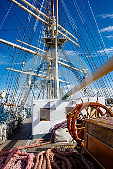 Sailship deck with helm, rigging and cables.
