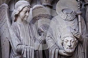 Saint Denis without head and angel, Notre dame detail in Paris, France