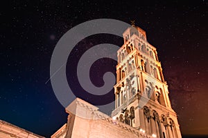 Saint Dominus belltower seen from below, long exposure, illuminated by orange lights at night, beautiful colorful night sky with