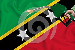 SAINT KITTS flag Close-up shot on waving background texture with Fuel pump nozzle in hand. The concept of design solutions. 3d
