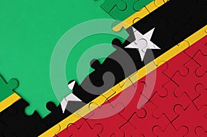 Saint Kitts and Nevis flag is depicted on a completed jigsaw puzzle with free green copy space on the left side