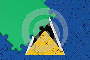 Saint Lucia flag is depicted on a completed jigsaw puzzle with free green copy space on the left side