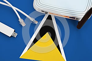 Saint Lucia flag depicted on table with internet rj45 cable, wireless usb wifi adapter and router. Internet connection concept