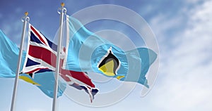 Saint Lucia national flags waving with United Kingdom flag on a clear day