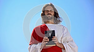 Saint man holding Bible against sky, faith and religion concept, catholicism