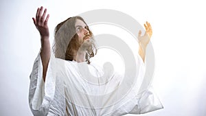 Saint man in robe raising hands to light, praying to God, religious conversion