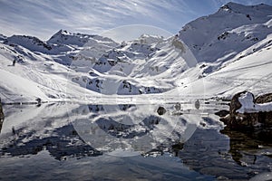 The snow-covered mountain and its reflection in Lac du Lou near Val Thorens resort photo
