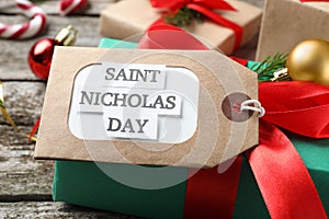 Saint Nicholas Day. Gift box with tag on wooden table, closeup