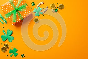 Top view photo of big giftbox with bow gold coins horseshoe straws shamrocks and trefoil shaped