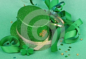 Saint Patrick`s Day image of sparkly green and gold leprechaun hat with curls of green and gold ribbon on a green background with