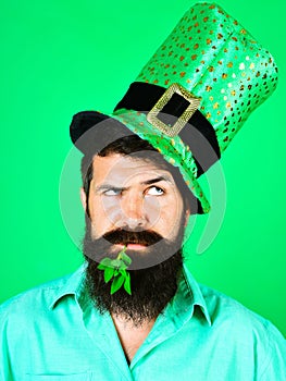 Saint Patrick's Day man. Bearded man in leprechaun hat with clover in mouth. Pensive man in top green hat. Ireland