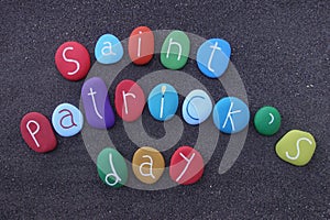 Saint Patrick`s day with multicolored painted stones over black sand