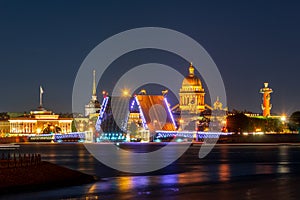 Saint Petersburg cityscape with open Palace bridge, St. Isaac`s cathedral, Admiralty building and Rostral column at night, Russia