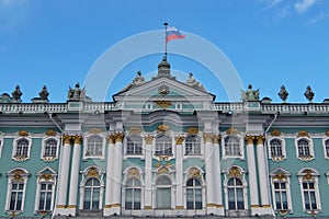 Sunny day in Saint-Petersburg, russian flag flying above facade of Hermitage State Museum