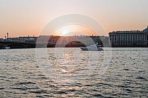 Saint-Petersburg, Russia, July 2021: A tourist boat sails along the Neva River at sunset, with the Annunciation Bridge