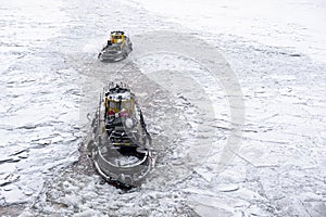 Saint Petersburg, Russia - 28.01.2022 two small vintage icebreaker ships make their way through a frozen icy river