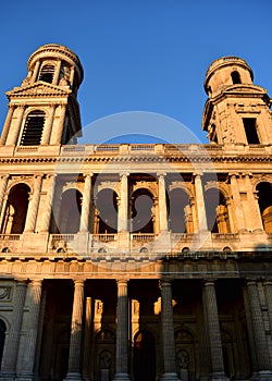 Saint Sulpice Church, Paris, France. Neoclassical facade with sunset light. Blue sky.