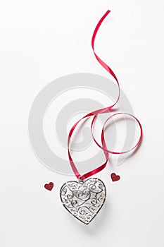 Saint Valentine day greeting card, beautiful silver heart with little red hearts with ribbon on white