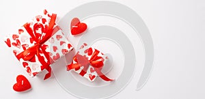 Saint Valentine`s Day concept. Top view photo of stylish gift boxes with red ribbon bows and heart shaped candles on isolated