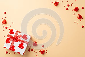 Saint Valentine`s Day concept. Top view photo of white giftbox with red ribbon bow heart shaped candies and sprinkles on isolated