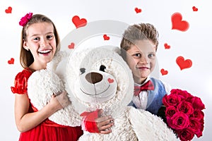 Saint Valentine`s day. Pretty girl with red dress and gentleman boy with blue vest, red butterfly tie, red roses bucket and heart