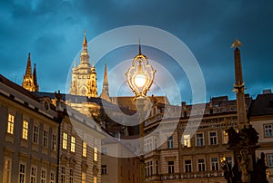 Saint Vitus Cathedral And Old Buildings With Bright Streetlight On Hradcany In Prague In The Czech Republic