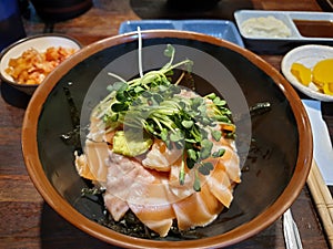 Sake-don, or Salmon donburi, Japanese traditional rice bowl dish topped with stacks of raw salmon belly, wasabi and sprout.